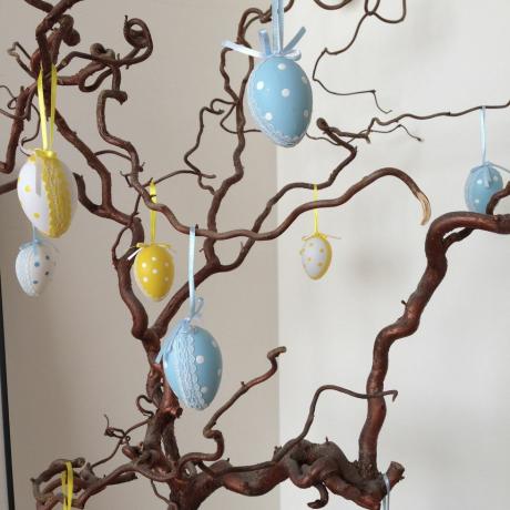 Graziose uova di pasqua appese all'albero al coperto