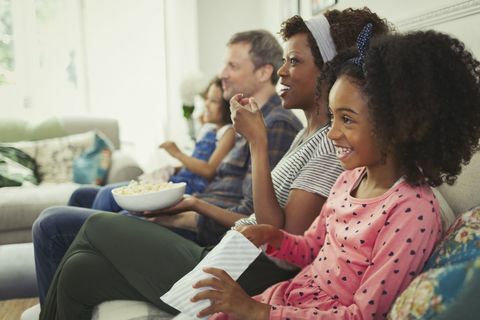 Giovane famiglia multietnica guardando film e mangiando popcorn sul divano