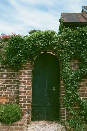 cancello del giardino con muro di mattoni coperto di edera