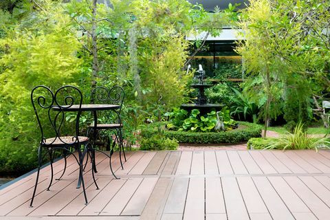 Sedia nera in patio di legno al giardino verde con fontana in casa. Giardino esterno.