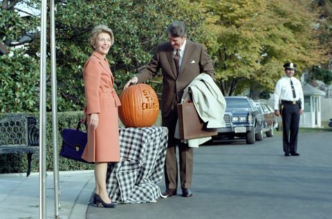 in questa fotografia, il presidente ronald reagan ammira una zucca intagliata con lo slogan " mantenere la rotta" il presidente reagan ha usato lo slogan durante il 1982 elezioni di medio termine la first lady Nancy Reagan posa accanto alla zucca i due sono in piedi fuori dal portico sud dell'ingresso al bianco Casa