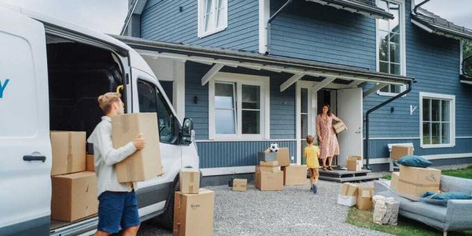 un giovane figlio aiuta i genitori a scaricare un furgone con mobili e accessori per la loro nuova casa in una zona residenziale di successo bambino che porta una pianta alla madre la famiglia si trasferisce nella nuova casa