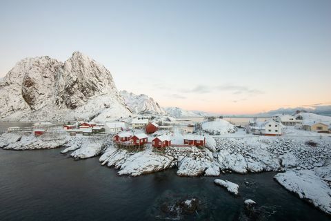 Villaggio rosso della casa di pesca fra la neve con il Mountain View nell'isola Hamnoy Norvegia di Lofoten