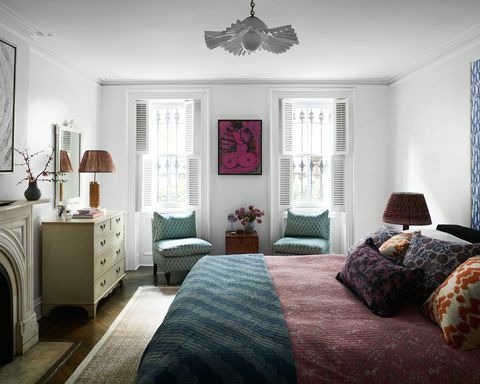 camera da letto, sedie blu, biancheria da letto rossa, tappeto verde, cuscini decorativi, caminetto, plafoniera bianca