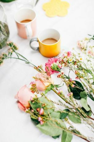 Tavolo con fiori recisi e tazze di caffè al laboratorio di organizzazione dei fiori