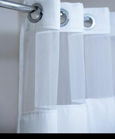 tenda da doccia bianca appesa a un'asta cromata per tenda da doccia
