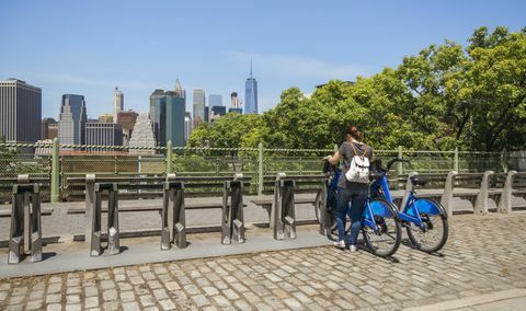 Donna che prende una bici davanti all'orizzonte di Manhattan a New York City