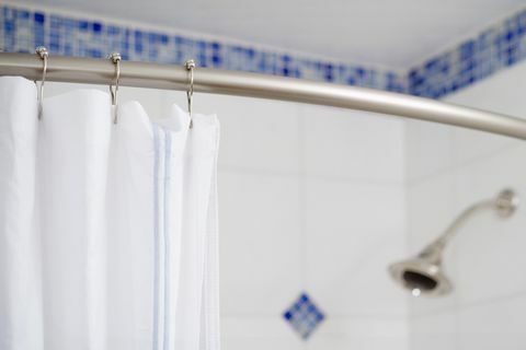 Dettaglio tenda da doccia e soffione doccia in piastrelle piastrellate bianche e blu