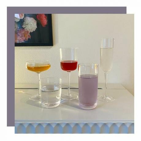 Assortimento di bicchieri di forma diversa sul tavolino con pittura floreale appesa al muro
