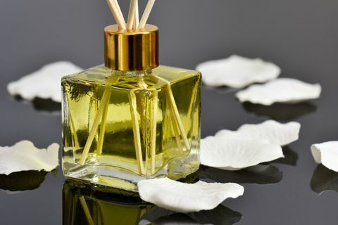 Deodorante per diffusore a cannella profumato alla vaniglia e petali di rosa su superficie riflettente.