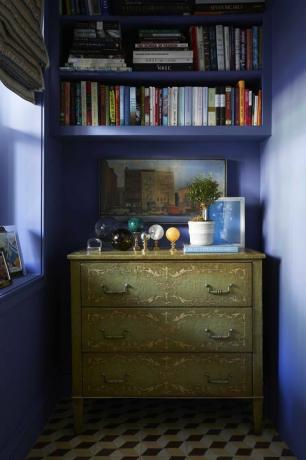 pareti dipinte di blu, cassettiera verde, palline di marmo, libri decorativi, pianta in vaso bianca