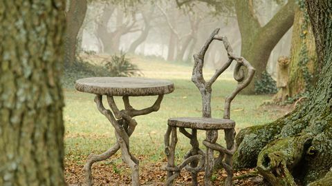 l'immagine di una sedia e di un tavolo finto bois tra gli alberi in una giornata nebbiosa