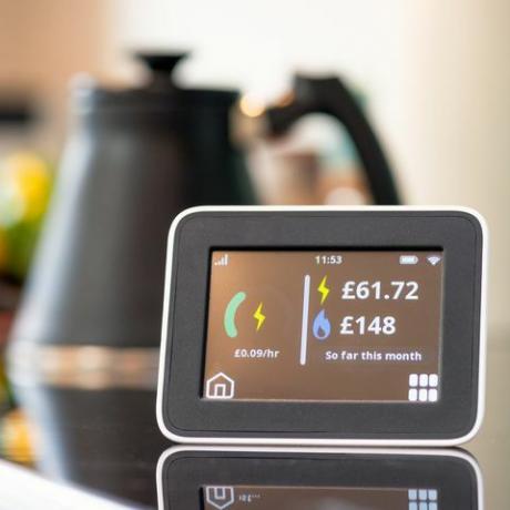 primo piano dello schermo di un contatore intelligente in una cucina, che mostra il costo mensile di elettricità e gas finora