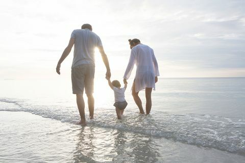 una famiglia mano nella mano che cammina lungo la spiaggia