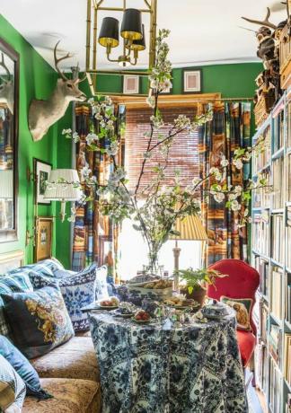 tinello, pareti dipinte di verde, testa di cervo, libreria con libri,