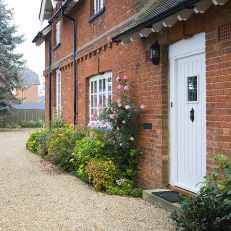 casa di campagna inglese e giardino in autunno con un vialetto di ghiaia la casa è di epoca vittoriana, con aiuole piene di arbusti e piante perenni