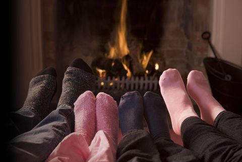 Piedi (calzini grigi, blu navy e rosa) davanti a una stufa a legna