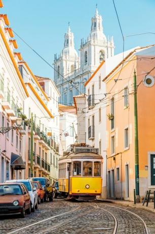 tram giallo sulla strada stretta del distretto di alfama a lisbona, portogallo