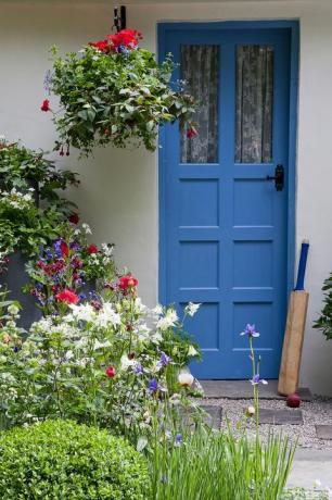 Porta d'ingresso blu con mazza da cricket e fioriere