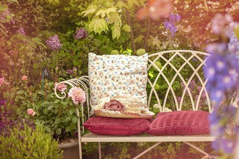 Una bella sedia da giardino estiva in ghisa con cuscini e un cappello estivo, scena shabby chic