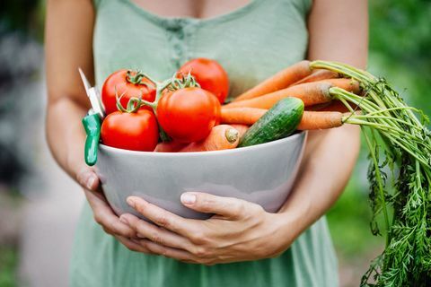 Primo piano di una donna che tiene una ciotola con le verdure appena raccolte