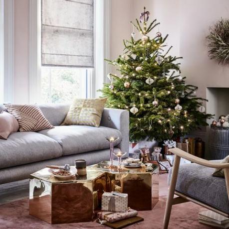 albero di natale in un angolo di un divano grigio soggiorno e tavolini esagonali oro, pareti rosa chiaro e grigio romano bui, gloria riflessa, stupefacente, specchiato, tavoli in ottone, bronzo e rosa, biglie, e accenti, portamento dell'oro, amoderno, pulenza toarelaxedsoggiorno